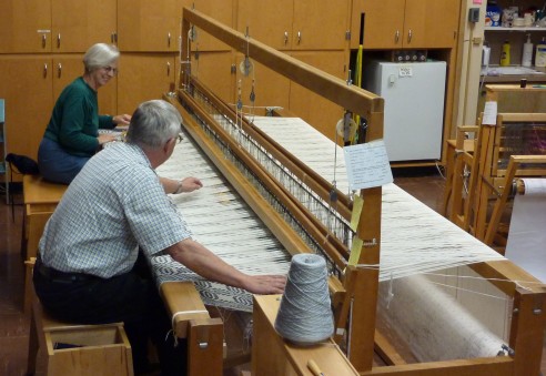 Members weave a coverlet together on the 120 inch loom at the Guild studio.
